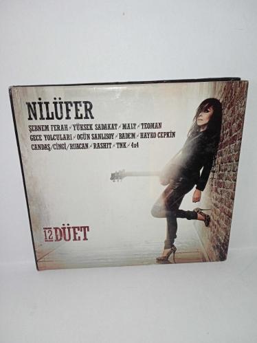Cd Nilüfer 12 Düet Albümü. Nilüfer'in Rock düetlerinden oluşan albümüdür. Dinlemeyi etkilemeyen yoğun çizikler var. Baştan sona dinlendi sorunsuz çalışıyor.  Hayko Cepkin, Şebnem ferah, yüksek sadakat, malt, Teoman, gece yolcuları, Ogün Sanlısoy, Badem, Rashit, TNK, Candaş Cingi Ruacan, 4X4