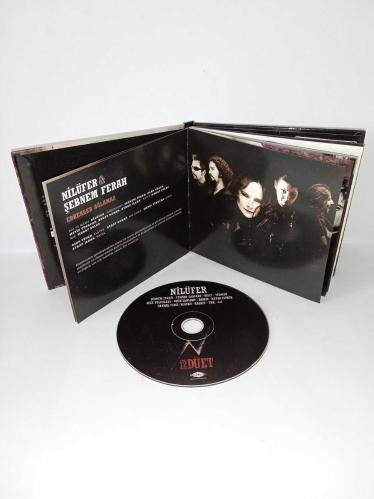 Cd Nilüfer 12 Düet Albümü. Nilüfer'in Rock düetlerinden oluşan albümüdür. Dinlemeyi etkilemeyen yoğun çizikler var. Baştan sona dinlendi sorunsuz çalışıyor.  Hayko Cepkin, Şebnem ferah, yüksek sadakat, malt, Teoman, gece yolcuları, Ogün Sanlısoy, Badem, Rashit, TNK, Candaş Cingi Ruacan, 4X4
