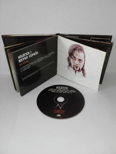Cd Nilüfer 12 Düet Albümü. Nilüfer'in Rock düetlerinden oluşan albümüdür. Dinlemeyi etkilemeyen yoğun çizikler var. Baştan sona dinlendi sorunsuz çalışıyor.  Hayko Cepkin, Şebnem ferah, yüksek sadakat, malt, Teoman, gece yolcuları, Ogün Sanlısoy, Badem, Rashit, TNK, Candaş Cingi Ruacan, 4X4