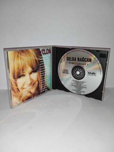 Cd Selda Bağcan Moğollar 1971 Türkülerimiz 1 albümü. Orijinal. Majör dönem baskı albümü. Disk 10 üzerinden 9.5 temiz Sorunsuz çalışıyor koleksiyonluk.  Katip Arzuhalim Yaz Yare Böyle, Adaletin Bu Mu Dünya, Çemberimde Gül Oya, Yalan Dünya, Kalenin Dibinde Taş Ben Olaydım, Tatlı Dillim, Mapushanelere Güneş Doğmuyor, Mapushane İçinde Mermerden Direk, Dane Dane Benleri, Gesi Bağları, Altın Kafes, Bülbül, Bölemedim Felek İle Kozumu, Eyvah Gönül Sana Eyvah, Anayasso, Nem Kaldı, O Günler
