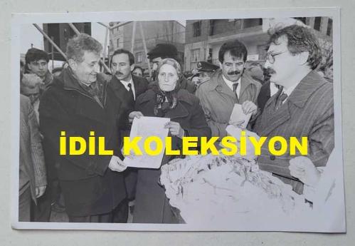 TÜRKİYE CUMHURİYETİ ESKİ SAĞLIK BAKANI YILDIRIM AKTUNA'NIN ORİJİNAL AJANS-BASIN FOTOĞRAFI - 18 x 12 cm EBADINDA - YILDIRIM AKTUNA, BELEDİYE BAŞKANINDAN TAPUSUNU ALAN HADİYE KÜRKÇÜ İLE KONUŞURKEN ÇEKİLMİŞ BİR KARE. 28 ŞUBAT 1991. HASAN KARAKAŞ